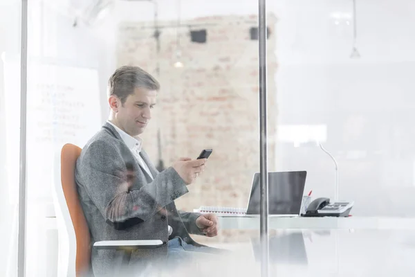 オフィスで座りながらスマート フォンを使用して自信を持ってマネージャー — ストック写真