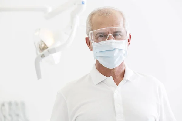 牙科诊所戴口罩和眼镜的资深牙医肖像 — 图库照片
