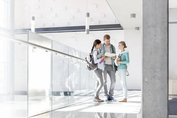 Amici Che Comunicano Attraverso Libro Mentre Piedi Corridoio Università — Foto Stock