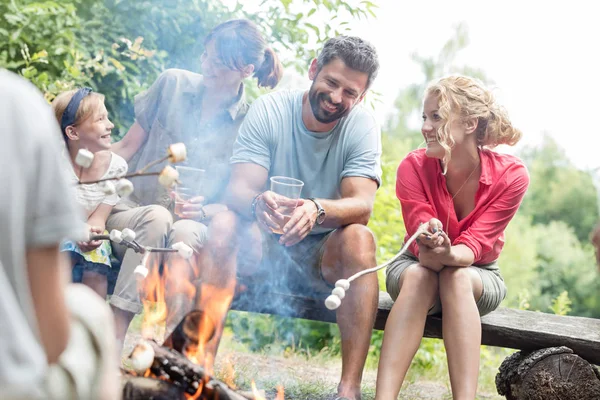 Szczęśliwa Rodzina Siedzi Kobietą Podczas Pieczenia Marshmallows Nad Płonącym Ognisku — Zdjęcie stockowe