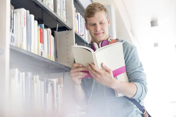 Estudiante Sonriente Leyendo Libro Por Estante Biblioteca Universidad —  Fotos de Stock