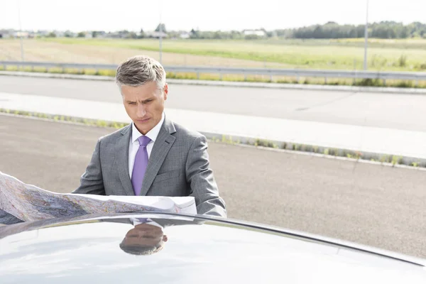 Σοβαροί Επιχειρηματία Ανάγνωση Χάρτη Έξω Από Αυτοκίνητο Ενώ Στέκεται Στον — Φωτογραφία Αρχείου