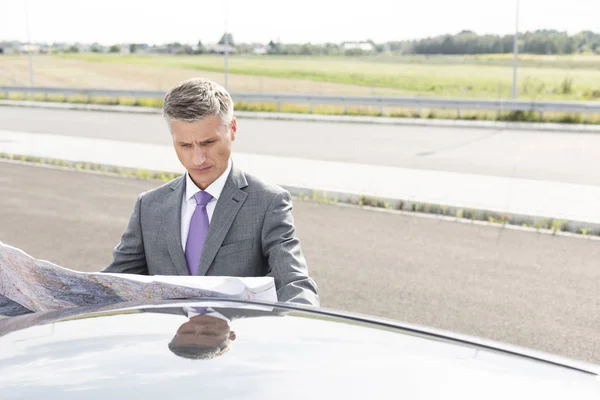 Ernstige Zakenman Lezen Van Kaart Buiten Auto Terwijl Weg — Stockfoto