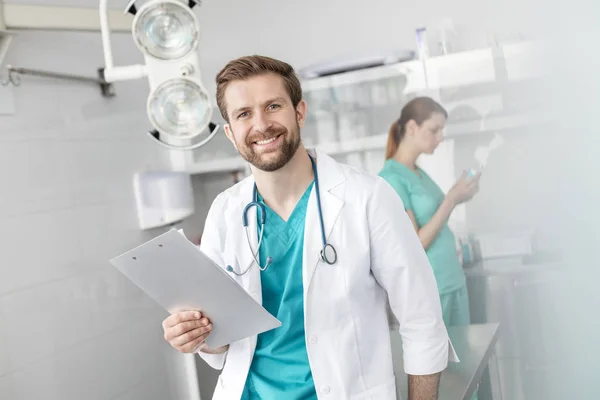 Retrato Médico Sorridente Segurando Prancheta Enquanto Está Contra Colega Trabalho — Fotografia de Stock