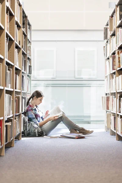 Adolescente Leyendo Libro Mientras Está Sentado Contra Los Estantes Biblioteca —  Fotos de Stock