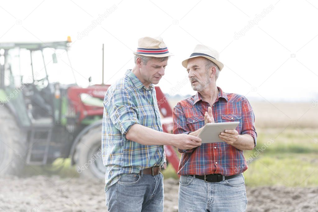 Farmers with digital tablet discussing at farm