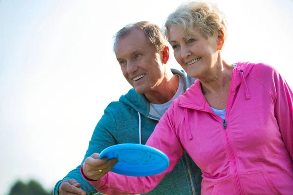 Loving active couple throwing flying disc together in park