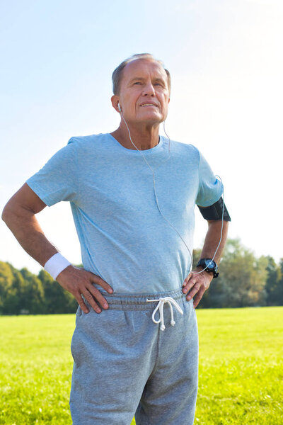 Active senior man standing with hands on hips in park