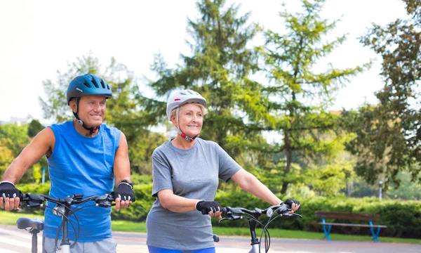 Pasująca Para Seniorów Spacerująca Rowerami Parku — Zdjęcie stockowe