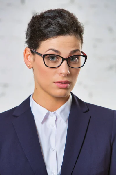 Portrait of curious businesswoman wearing eyeglasses against brick wall