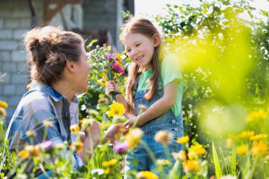 Çiftlik at bahçe sırasında çiçekler bakarak gülümseyen anne ve kızı