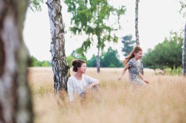 Tarlada koşan kızına bakan bir kadın.