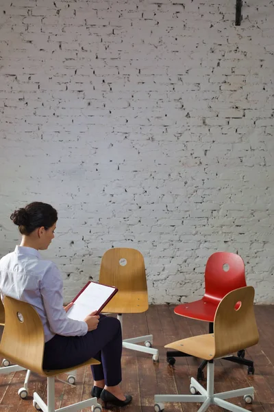Kadını Ofis Lobisinde Beyaz Tuğla Duvarın Karşısında Oturuyor — Stok fotoğraf