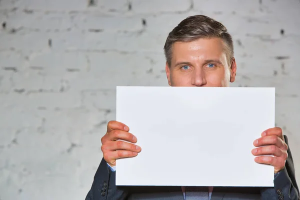 Midsection Businessman Holding Blank Placard While Standing White Brick Wall — Stock Photo, Image