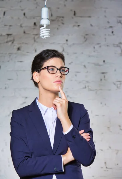 Junge Nachdenkliche Geschäftsfrau Betrachtet Energieeffiziente Glühbirne Die Büro Einer Ziegelwand — Stockfoto