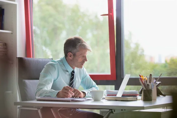 Seriöser Geschäftsmann Mit Laptop Während Schreibtisch Büro Papierkram Erledigt — Stockfoto