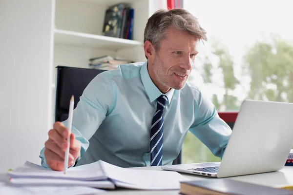 Homem Negócios Sorrindo Usando Laptop Enquanto Fazendo Papelada Mesa Escritório — Fotografia de Stock
