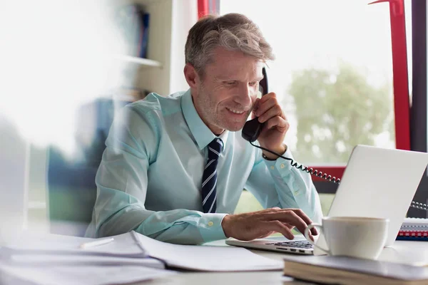 Улыбающийся Бизнесмен Разговаривает Телефону Время Использования Ноутбука Офисе — стоковое фото