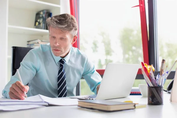 Hombre Negocios Serio Usando Ordenador Portátil Mientras Hace Papeleo Escritorio — Foto de Stock