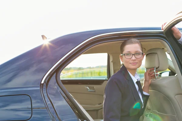 空に対して女性同僚のための車のドアを保持する熟女ビジネス女性 — ストック写真