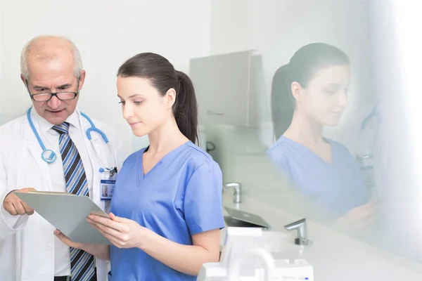 Doctor examining medical report with nurse at dental clinic