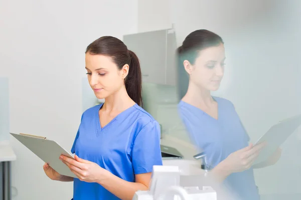 Nurse reviewing medical report on clipboard at dental clinic — Stock Photo, Image