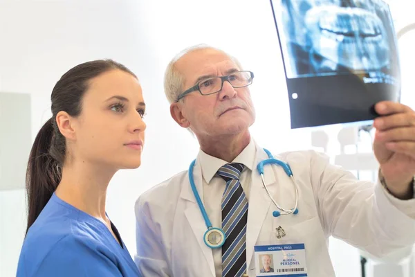 Médico examinando rayos X médicos con enfermera en clínica dental —  Fotos de Stock