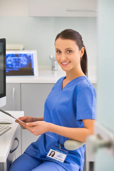 Portrait of confident smiling nurse with clipboard at dental cli — Foto Stock