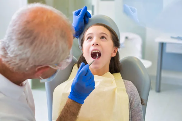 Dentista examinando paciente con equipo en clínica dental —  Fotos de Stock