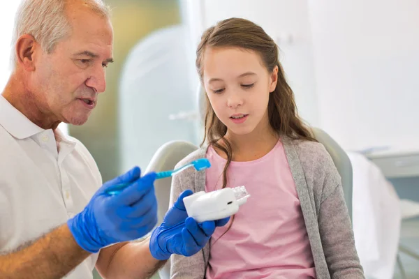 Arzt lehrt Kinderpatienten, wie man Zähne richtig putzt — Stockfoto