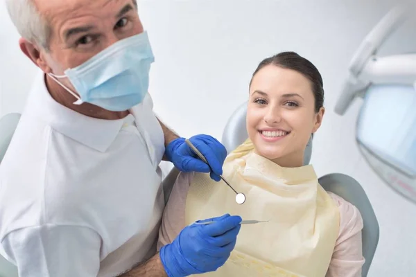 Hög vinkel syn på tandläkare undersöka patienten med tandläkarutrustning — Stockfoto