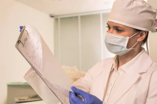 Arzt trägt Gesichtsmaske und Mütze bei Untersuchung des medizinischen Ergebnisses — Stockfoto