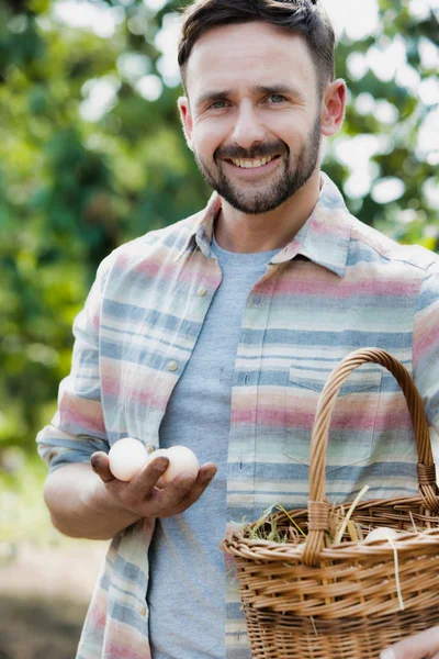 在农场的篮子里拿着鸡蛋的微笑的农民的肖像 — 图库照片