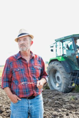Kendine güvenen üst düzey Çiftçi traktör çiftliğinde karşı daimi portresi