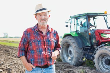 Kendine güvenen üst düzey Çiftçi traktör çiftliğinde karşı daimi portresi