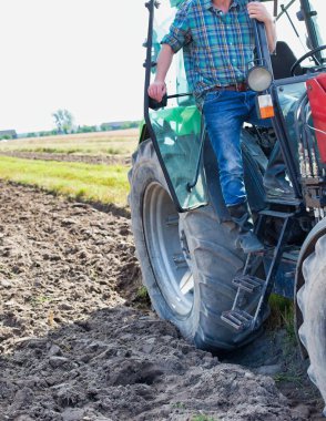 Çiftçinin tarlada gökyüzüne karşı durduğu hasat makinesi