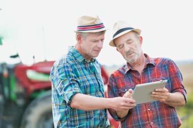 Gülümseyen çiftçiler çiftliğinde dijital tablet üzerinden iletişim