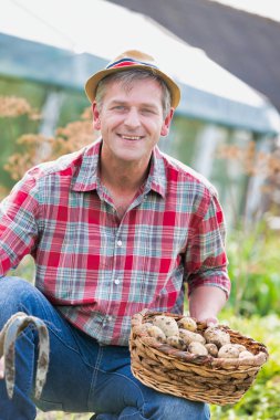 Çiftçi çiftlikte taze patates tutuyor.
