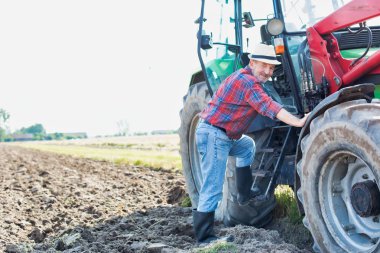 Çiftlikte traktör açan kendinden emin yaşlı çiftçinin portresi