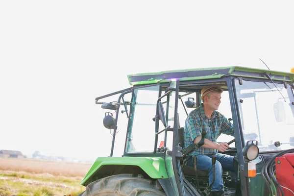 confident farmer driving tractor at farm