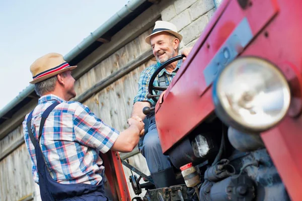 农民们在农场靠近拖拉机的地方握手 — 图库照片