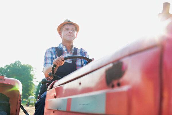 confident farmer driving tractor at farm