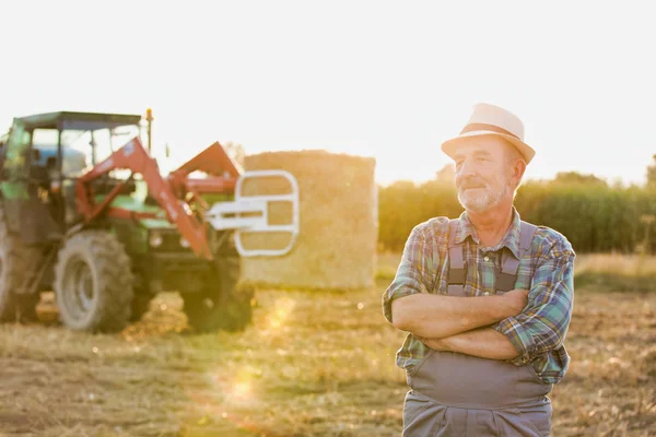自信的高级农夫的画像站立反对拖拉机在农场 — 图库照片