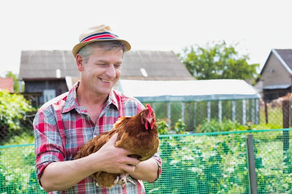 在农场抱着母鸡微笑的农民 — 图库照片