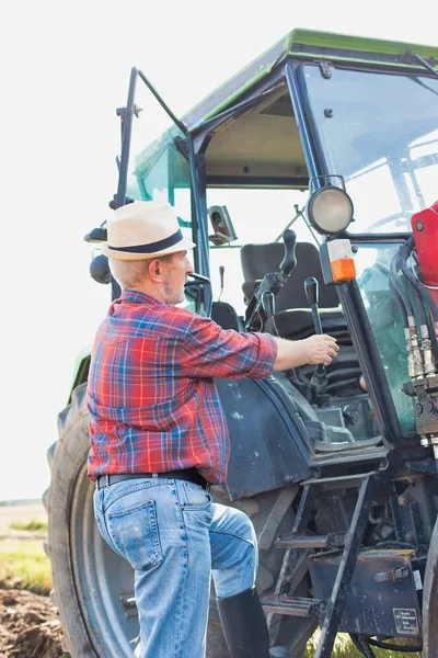 自信的老年农民在农场开拖拉机的画像 — 图库照片
