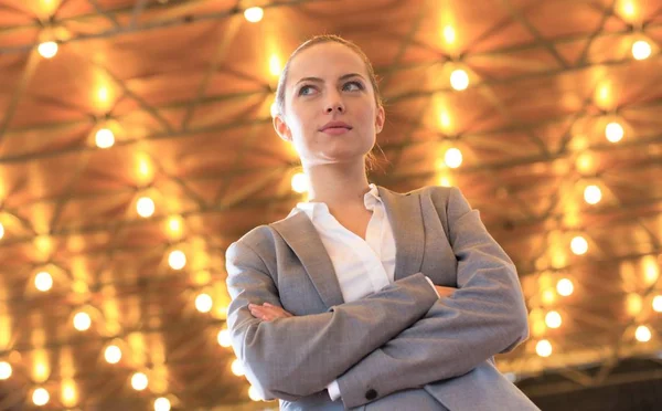 Confident young businesswoman standing with arms crossed against — Stock Photo, Image