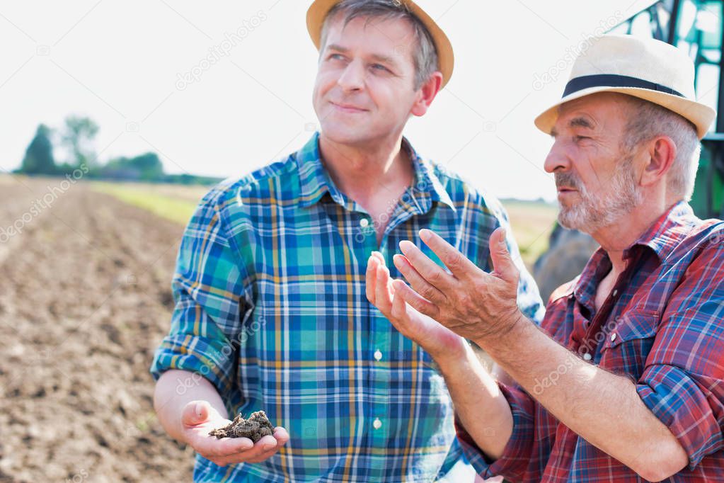 Farmers discussing over soil on field at farm