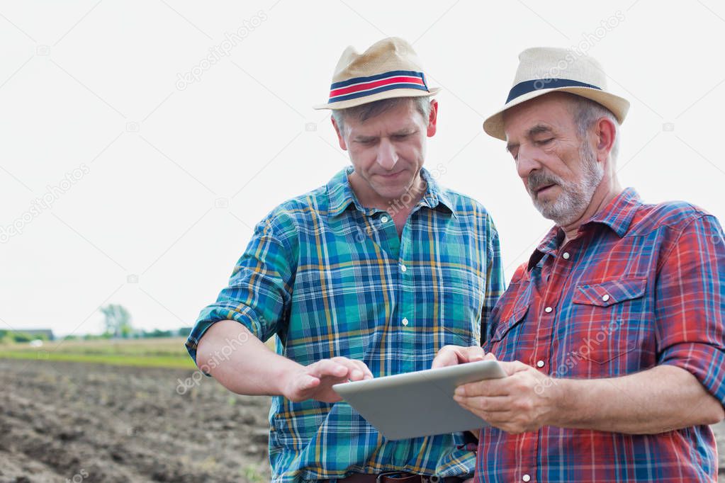 Smiling farmers communicating over digital tablet at farm