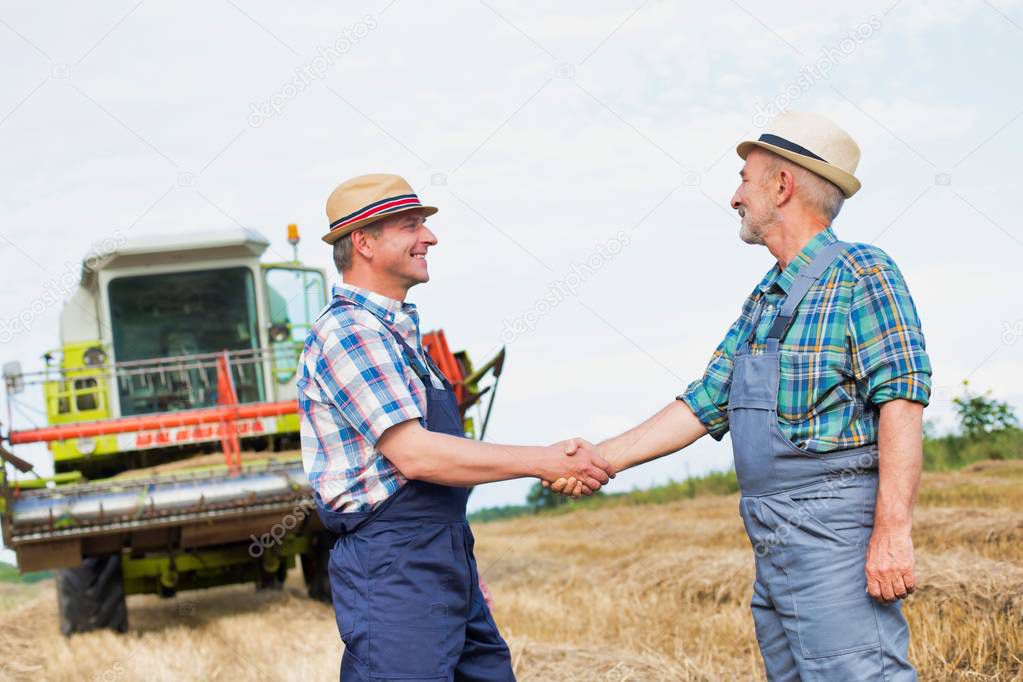 farmers shaking hands while standing on field at farm