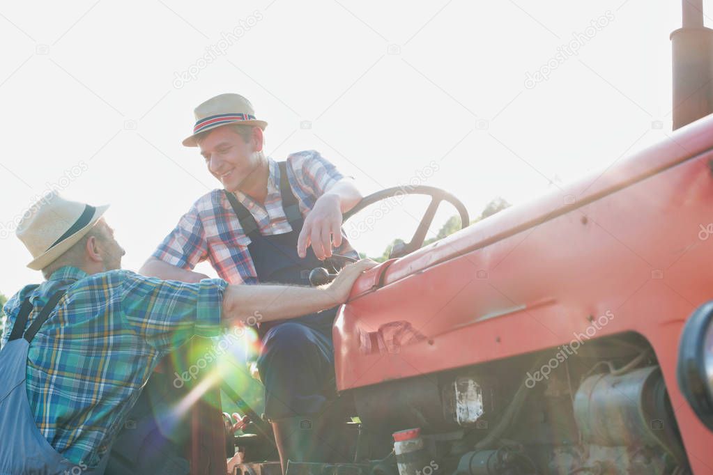 Farmers talking near tractor at farm